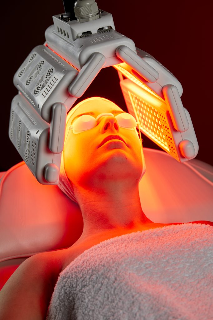 a woman receiving red LED light therapy on her face